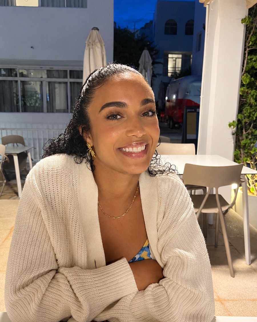 Rose, founder of HighHeart, smiling at a café table in the evening